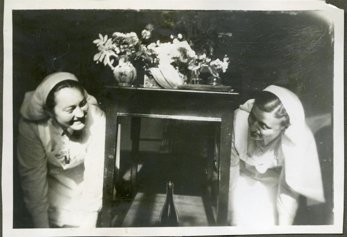 To sykepleiere hygger seg ved et bord  - Klikk for stort bilde