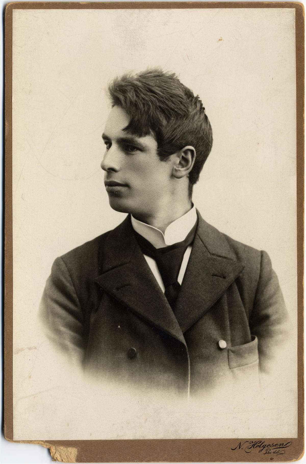 Portrett av mann med ansiktet i profil. Kledt i dress og slips med stivet krage på skjorta. - Klikk for stort bilde